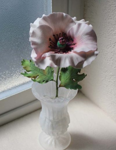 Used as a gift. A sugar vase with one white sugar poppy and two sugar leaves.